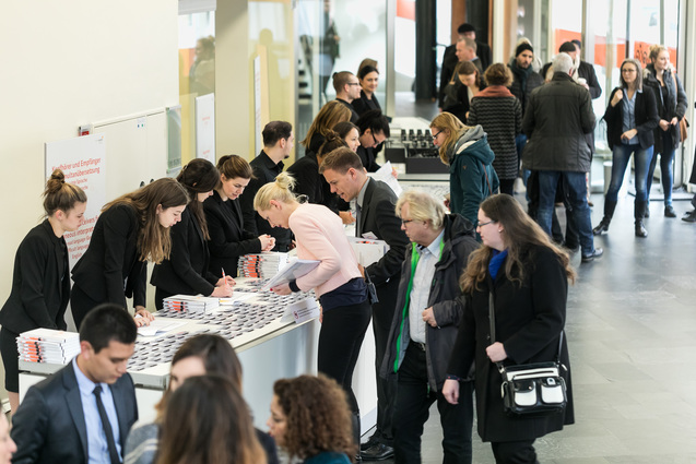 Auf dem Bild ist der Eingangsbereich des Berliner Congress Center zu sehen. Die Gäste nehmen ihre Namensschilder in Empfang.