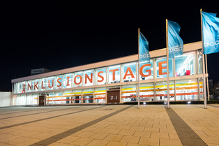 Auf dem Bild ist das hell erleuchtete Berliner Congress Center bei Nacht abgebildet. Auf der Fensterfront steht in Großbuchstaben das Wort Inklusionstage.